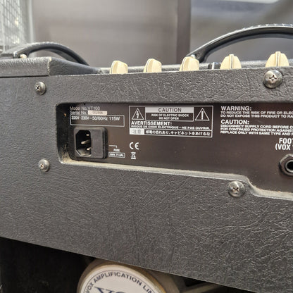 Pre-Owned Vox VT100 Valvetronix 100w Electric Combo Close-up of the rear power supply and input jack area of a black guitar amplifier, showing model markings and warning labels.