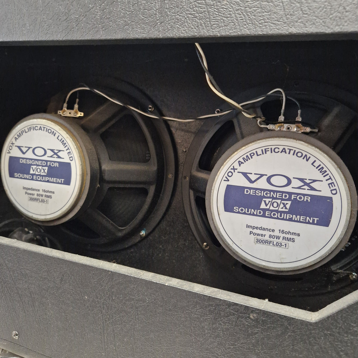 Pre-Owned Vox VT100 Valvetronix 100w Electric Combo Two VOX speaker drivers mounted inside a gray amplifier cabinet, with visible wiring and the VOX logo on the speaker cones.