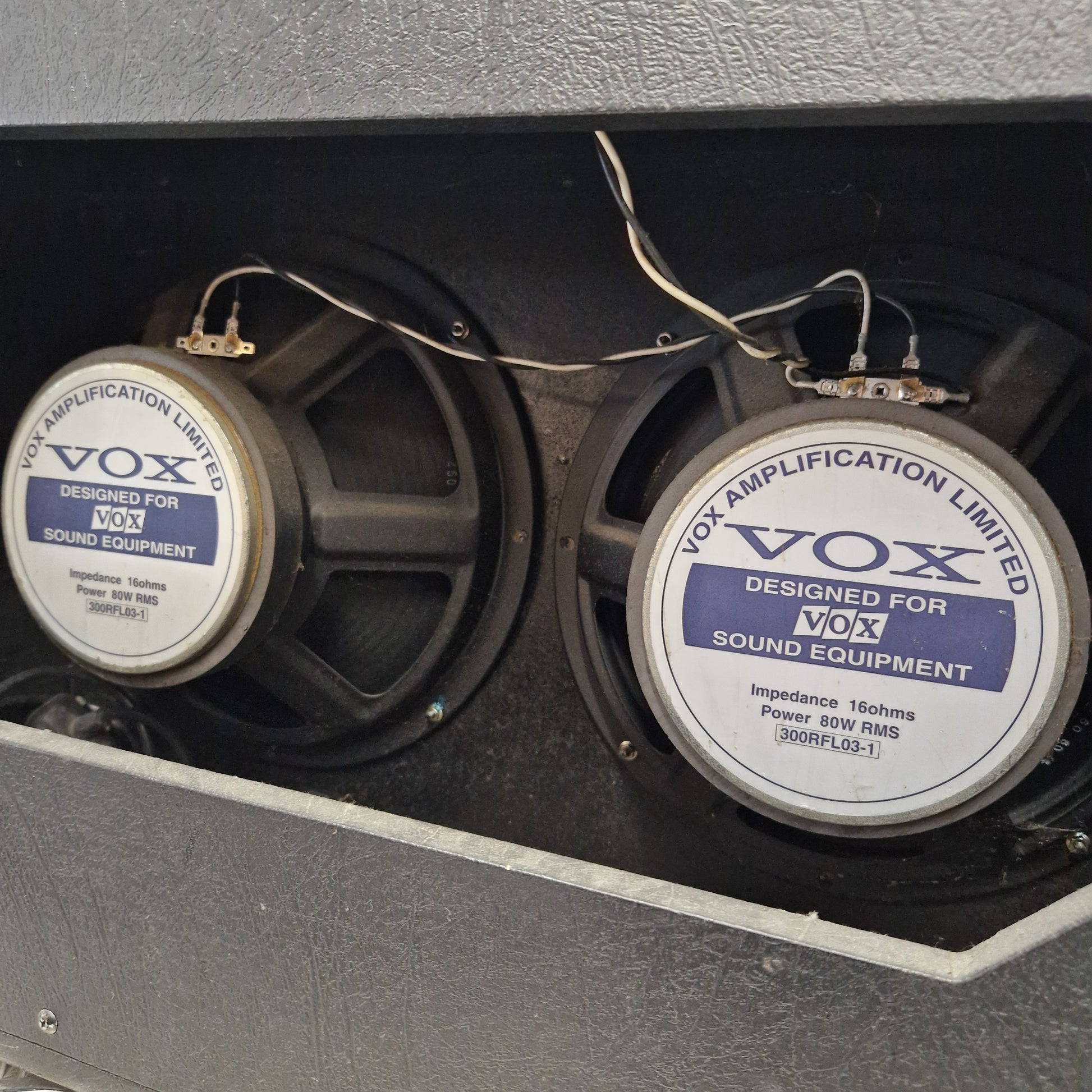 Pre-Owned Vox VT100 Valvetronix 100w Electric Combo Two VOX speaker drivers mounted inside a gray amplifier cabinet, with visible wiring and the VOX logo on the speaker cones.