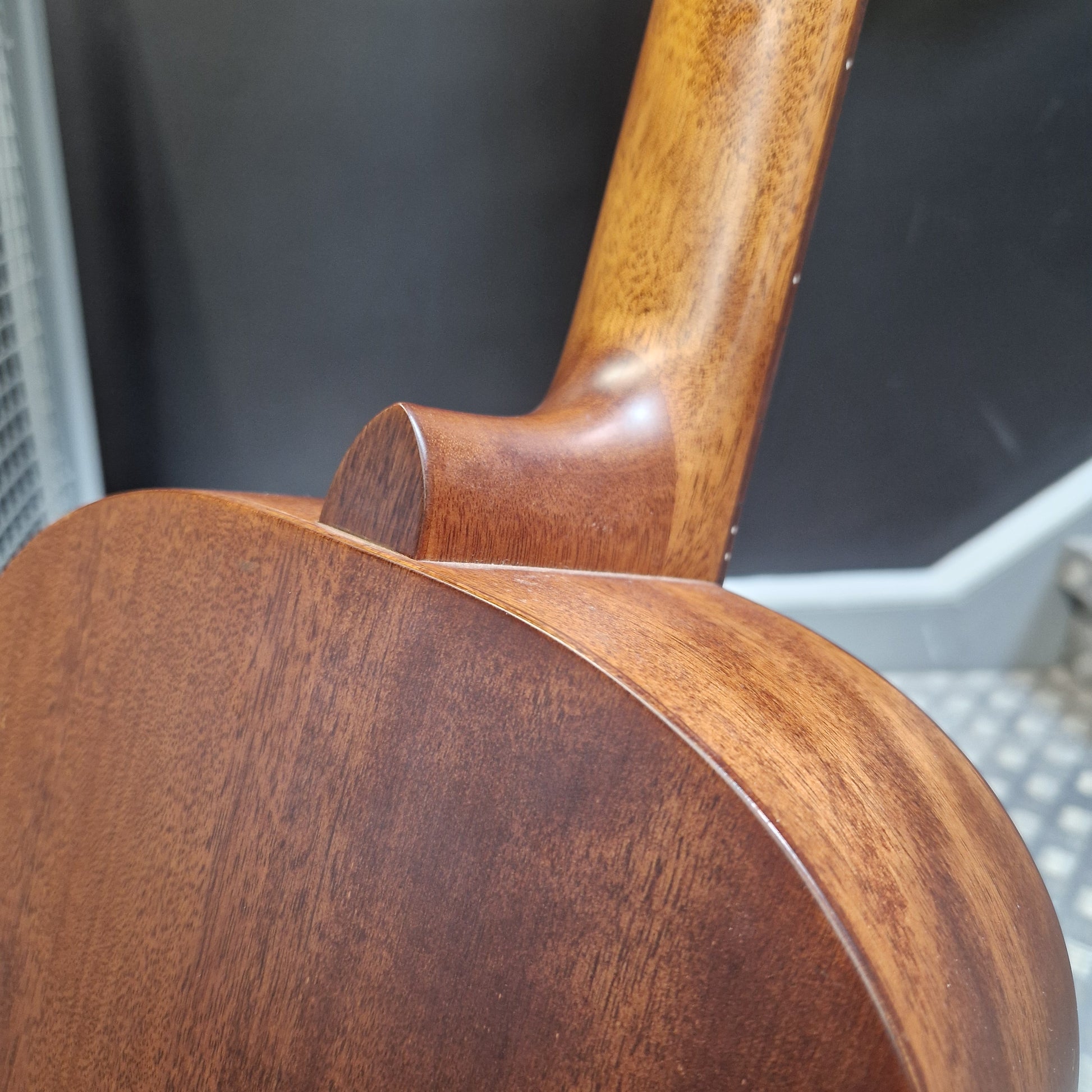 Pre-Owned Layke Smokestack Parlour Electro-Acoustic - Mahogany Close-up detail of a wooden acoustic guitar body and neck joint, showing the rich brown wood grain finish.