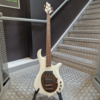 Pre-Owned Traben Neo 4 Bass - White A white electric bass guitar with a dark brown pickguard and maple neck, standing on a black stand in front of an indoor staircase.