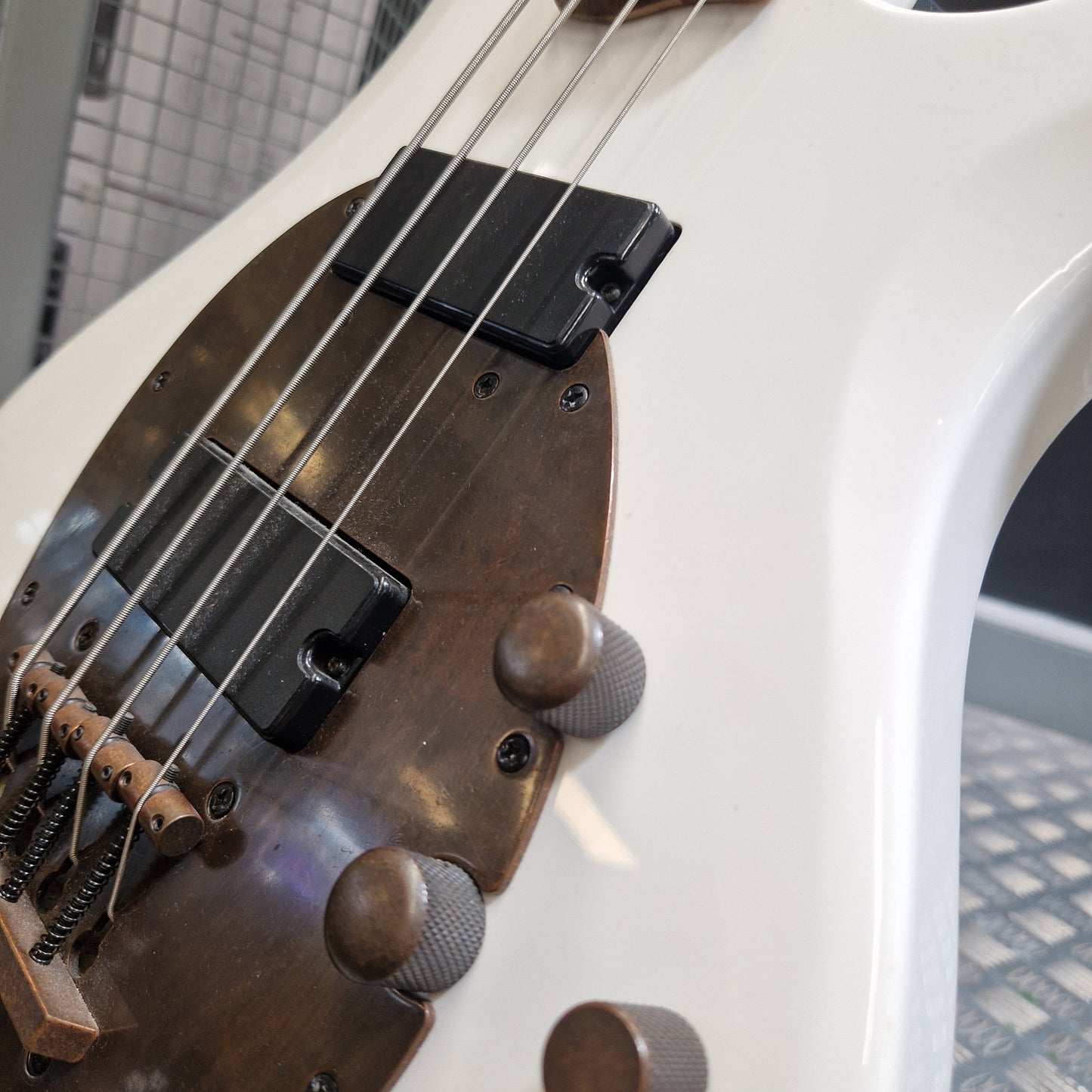 Pre-Owned Traben Neo 4 Bass - White Close-up of a white electric bass guitar body showing the brown pickguard, black pickups, metal strings, and part of the control knobs.