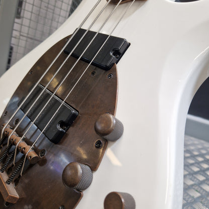 Pre-Owned Traben Neo 4 Bass - White Close-up of a white electric bass guitar body showing the brown pickguard, black pickups, metal strings, and part of the control knobs.