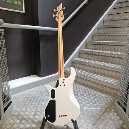 Pre-Owned Traben Neo 4 Bass - White A white electric bass guitar with a natural wood neck and black pickguard, standing on a stand in front of an indoor staircase.