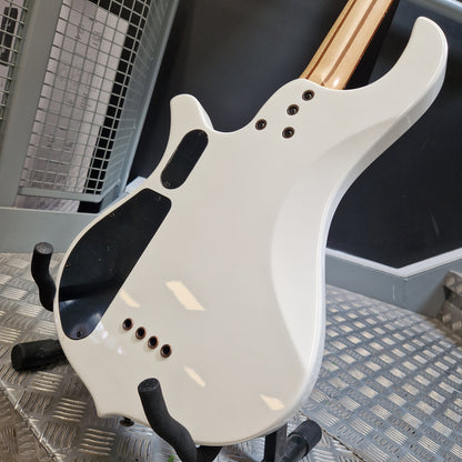 Pre-Owned Traben Neo 4 Bass - White Close-up of the back of a white electric guitar resting on a black stand on a metal diamond plate floor, with a dark wall and industrial background.