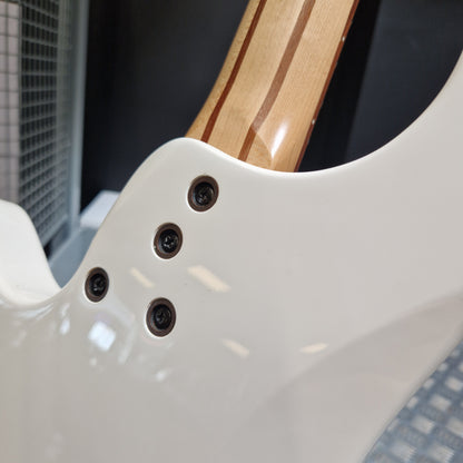 Pre-Owned Traben Neo 4 Bass - White Close-up of the lower bout body of a white electric guitar, showing four black control screws and part of the natural wood neck with dark stripes.