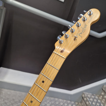 Pre-Owned Fender American Standard Telecaster 2000 Electric - 3-Colour Sunburst Close-up of a Fender Stratocaster electric guitar headstock and neck, showing the natural maple wood finish and six silver tuning pegs against a dark gray background.