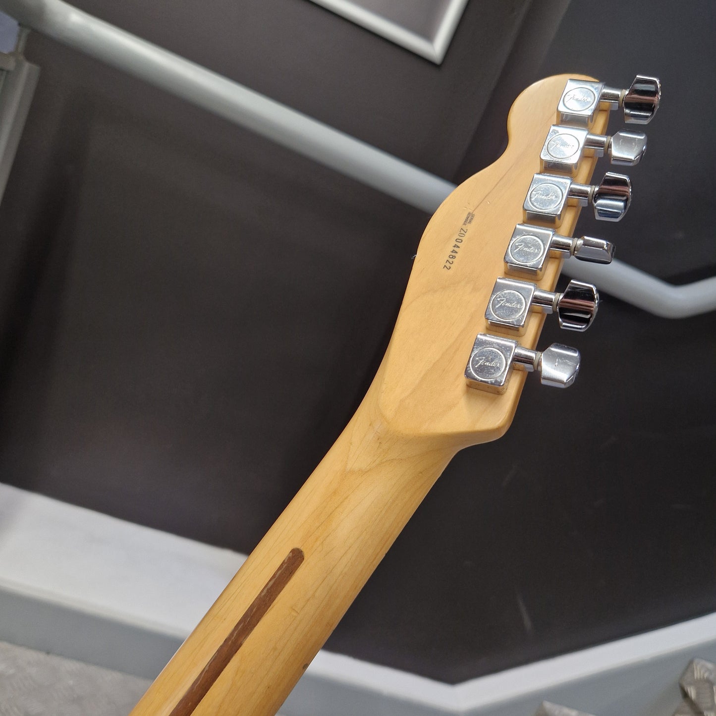 Pre-Owned Fender American Standard Telecaster 2000 Electric - 3-Colour Sunburst Close-up of the headstock of a Fender Stratocaster electric guitar in a natural maple finish, showing the six chrome tuning pegs and the Fender logo.