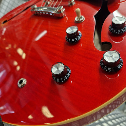 Pre-Owned Epiphone ES-335 Figured Semi-Hollow Electric - Sixties Cherry Close-up of a red electric guitar body showing control knobs, a toggle switch, and part of the bridge on a glossy finish.