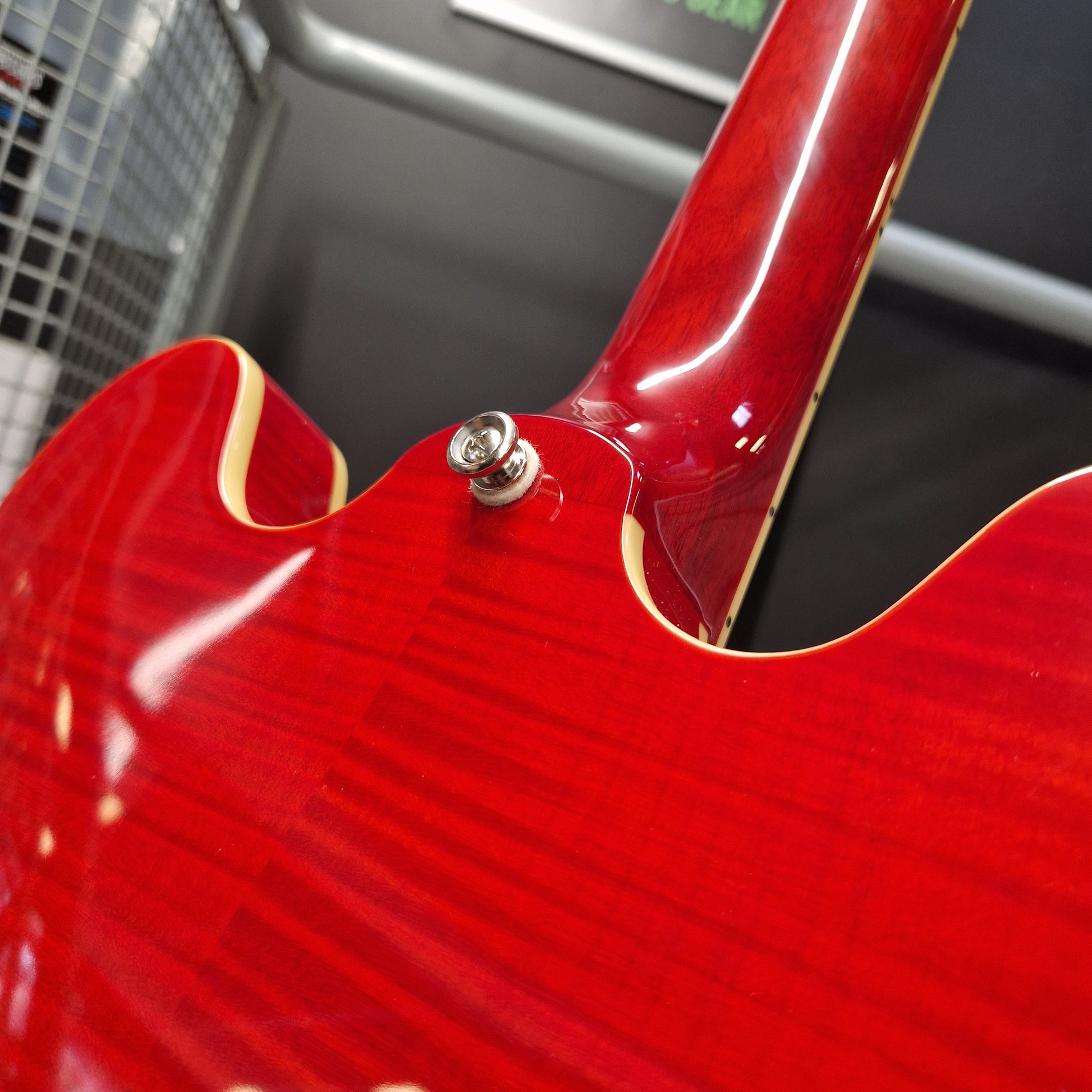 Pre-Owned Epiphone ES-335 Figured Semi-Hollow Electric - Sixties Cherry Close-up of the back of a glossy red electric guitar showing the tailpiece, body wood grain, and part of the neck.