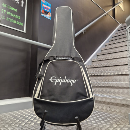 Pre-Owned Epiphone ES-335 Figured Semi-Hollow Electric - Sixties Cherry An Epiphone guitar gig bag standing upright on a stand in a real indoor environment with a staircase and wall signage visible in the background.