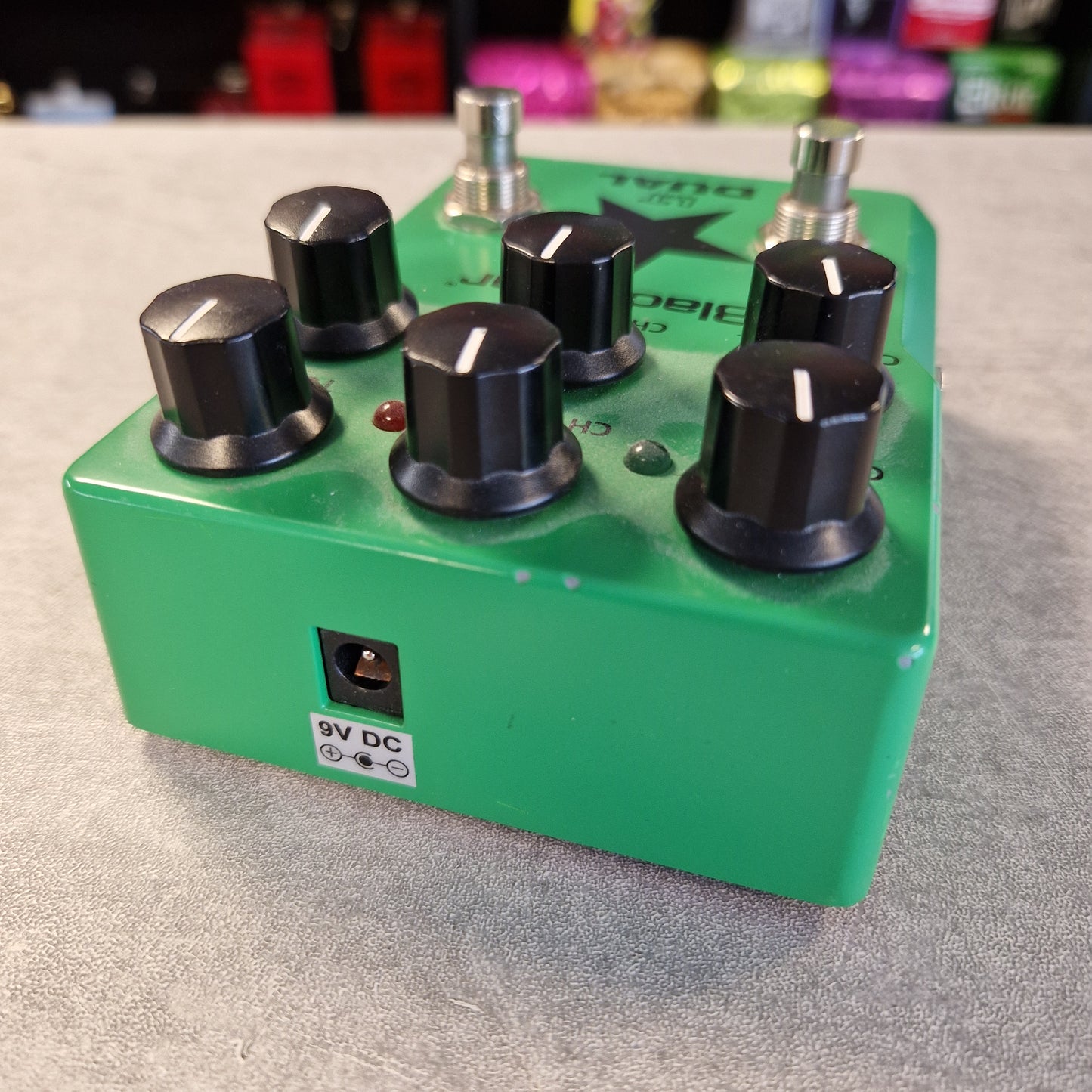 Pre-Owned Blackstar LT-DUAL Two-Channel Distortion Pedal A green dual channel audio effects pedal with six black knobs, silver metal footswitches, and a 9V DC power jack, shown on a gray textured surface.