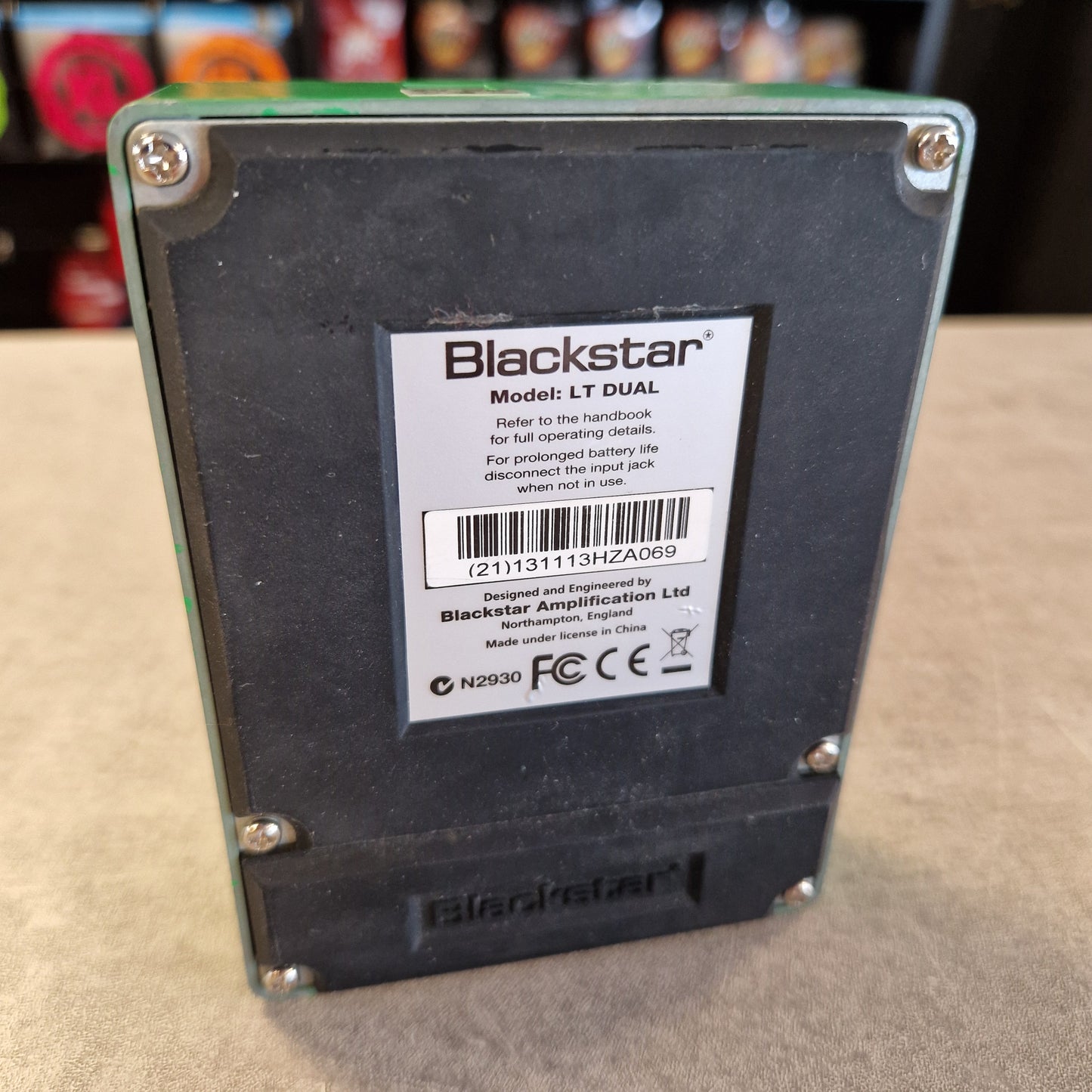 Pre-Owned Blackstar LT-DUAL Two-Channel Distortion Pedal Blackstar LT DUAL battery pack shown from the back, featuring a black label with white text and a barcode, secured with silver screws on a green circuit board base, set on a beige surface.