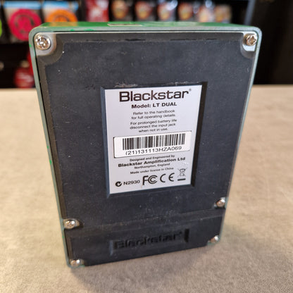 Pre-Owned Blackstar LT-DUAL Two-Channel Distortion Pedal Blackstar LT DUAL battery pack shown from the back, featuring a black label with white text and a barcode, secured with silver screws on a green circuit board base, set on a beige surface.