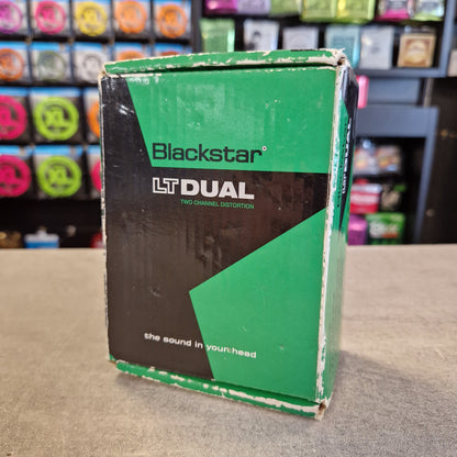 Pre-Owned Blackstar LT-DUAL Two-Channel Distortion Pedal A used Blackstar LT Dual two-channel distortion guitar pedal box, showing green and black packaging with white text, sitting on a gray tabletop with a blurred store background.
