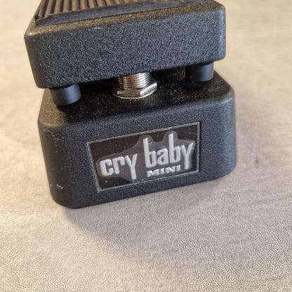 Pre-Owned Dunlop CBM95 Cry Baby Mini Wah Pedal A close-up shot of a black Cry Baby Mini guitar pedal on a textured gray surface.