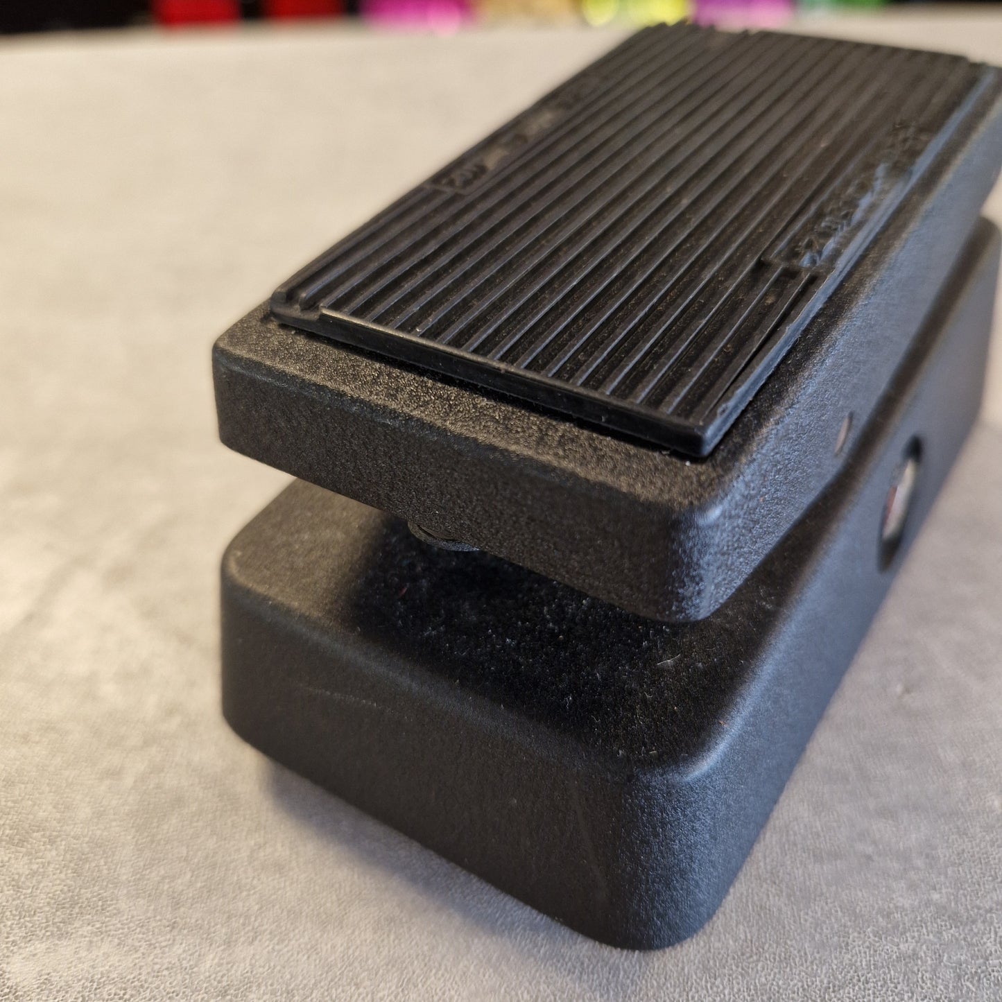 Pre-Owned Dunlop CBM95 Cry Baby Mini Wah Pedal A black textured metal guitar effects pedal with a ribbed footplate, photographed on a light gray surface.