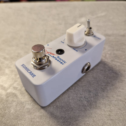 Pre-Owned Sonicake Super Sonic Master Boost Pedal A white Sonicake Somatic Master guitar effects pedal with chrome metal controls, photographed on a textured gray surface.