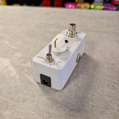 Pre-Owned Sonicake Super Sonic Master Boost Pedal A white guitar effects pedal with a white rotary knob, silver toggle switch, and silver metal inputs, resting on a gray textured surface.