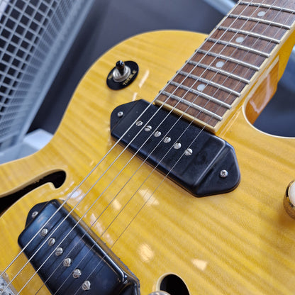 Pre-Owned Epiphone Wildkat Hollow-Body Electric - Natural Amber Close-up of a yellow-finish electric guitar body with black pickups, silver hardware, and part of the dark fretboard.