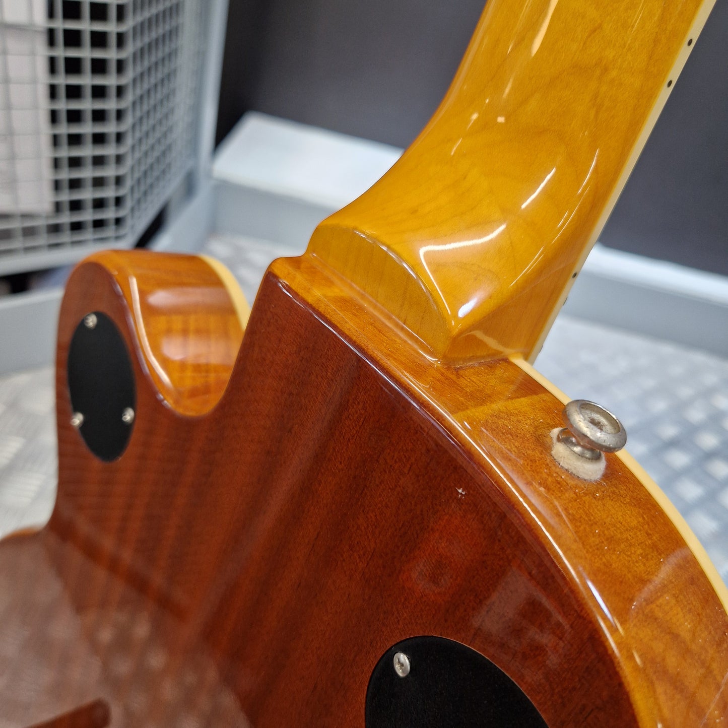 Pre-Owned Epiphone Wildkat Hollow-Body Electric - Natural Amber Close-up of the back of a glossy wood electric guitar, showing the body wood grain, black pickups, and the neck joint with a satin finish.