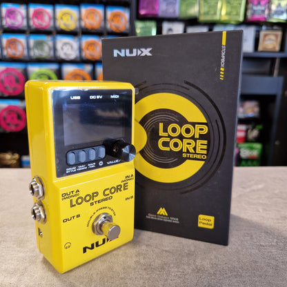 Pre-Owned Nux Loop Core Stereo Looper Pedal A yellow NUIX Loop Core Stereo guitar pedal in the foreground with its black retail box behind it, photographed on a tabletop with a blurred store background.