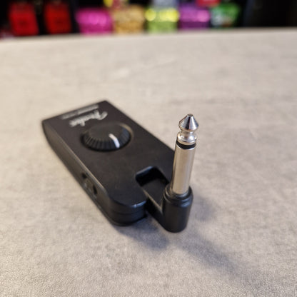 Pre-Owned Fender Mustang Micro Headphone Guitar Amplifier A black Fader wireless guitar pedal or signal conditioner with a 1/4-inch TS connector, resting on a gray textured surface with a blurred background.