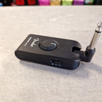 Pre-Owned Fender Mustang Micro Headphone Guitar Amplifier A black Fender speaker emulator/clipper device with a 1/4-inch jack plug attached, resting on a gray textured surface.