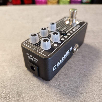 Pre-Owned Mooer 008 Cali-Mk3 Dual Channel Preamp Pedal A black Calhoun 3 guitar effects pedal with white and silver knobs, a footswitch, and white printed markings, resting on a gray textured surface.