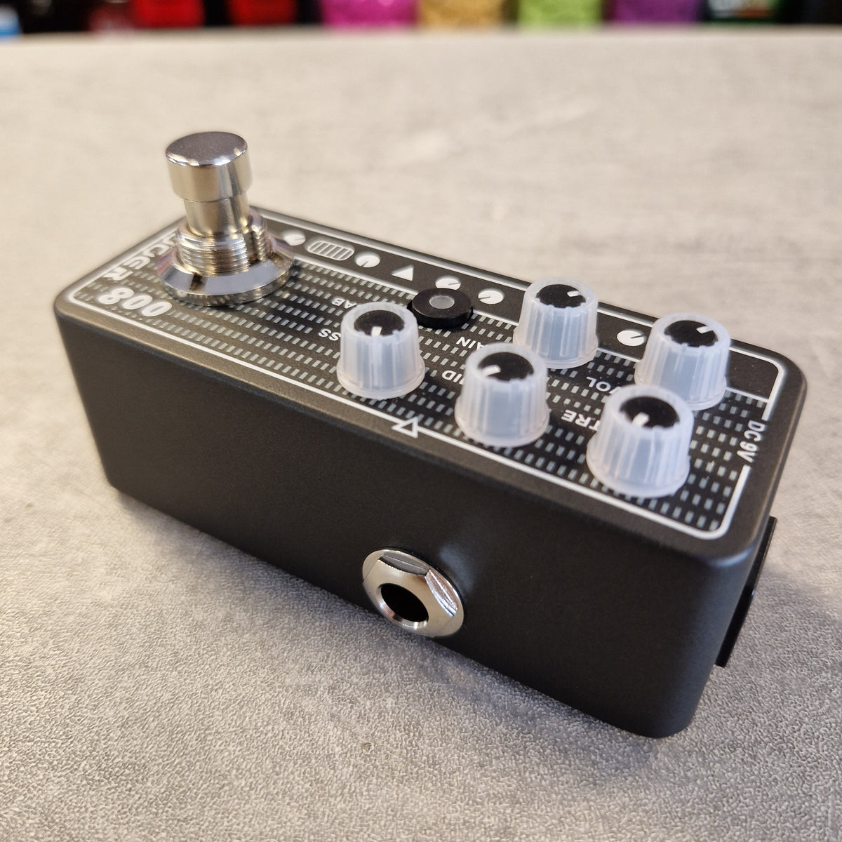Pre-Owned Mooer 008 Cali-Mk3 Dual Channel Preamp Pedal A black guitar effects pedal with a silver footswitch, white plastic knobs, and white printed markings, photographed on a gray textured surface.