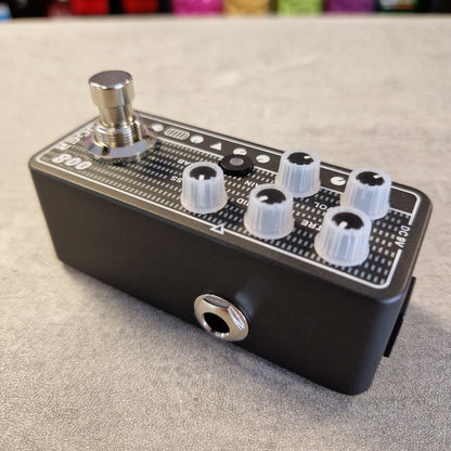 Pre-Owned Mooer 008 Cali-Mk3 Dual Channel Preamp Pedal A black guitar effects pedal with a silver footswitch, white plastic knobs, and white printed markings, photographed on a gray textured surface.