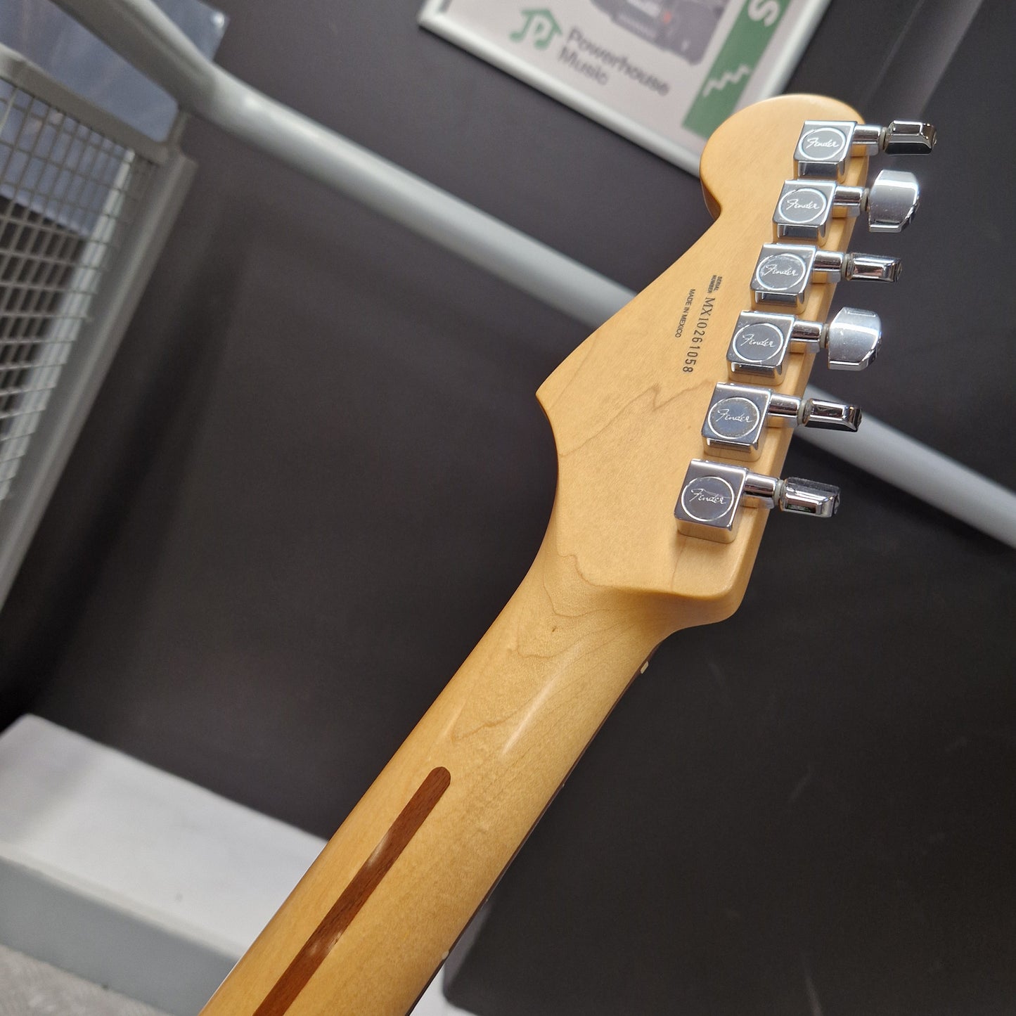 Pre-Owned Fender Standard Mexican Stratocaster 2011 Electric - Black Close-up of the headstock and neck of a Fender electric guitar in a natural maple finish, showing six silver tuning pegs and the Fender logo on the headstock.
