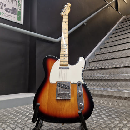 Pre-Owned Fender Player Telecaster 2022 Electric - 3-Colour Sunburst A classic Fender Telecaster electric guitar in a sunburst finish, displayed on a stand in front of a staircase.