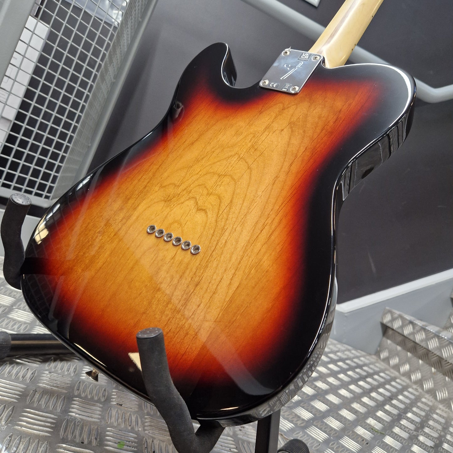 Pre-Owned Fender Player Telecaster 2022 Electric - 3-Colour Sunburst Close-up of the back of a sunburst electric guitar resting on a stand, showing the glossy wood finish, pickups, and part of the light-colored neck.