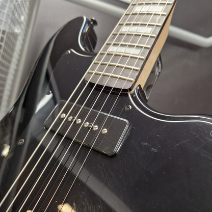 Pre-Owned Harley Benton JA-Baritone HH Electric - Black Close-up of a black electric guitar body and neck with a black single-coil pickup and metal strings, photographed indoors against a dark gray background.