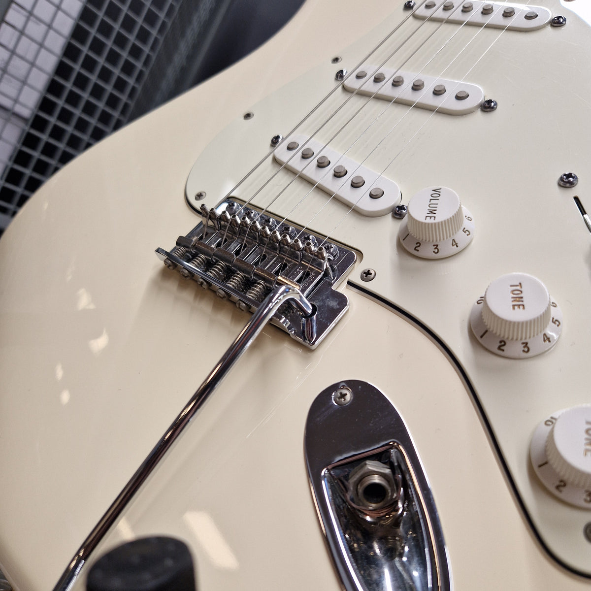 Pre-Owned Fender Standard Strocaster 2014 Electric - Arctic White Close-up of a cream-colored electric guitar body showing the bridge, pickups, volume and tone knobs, and chrome hardware.
