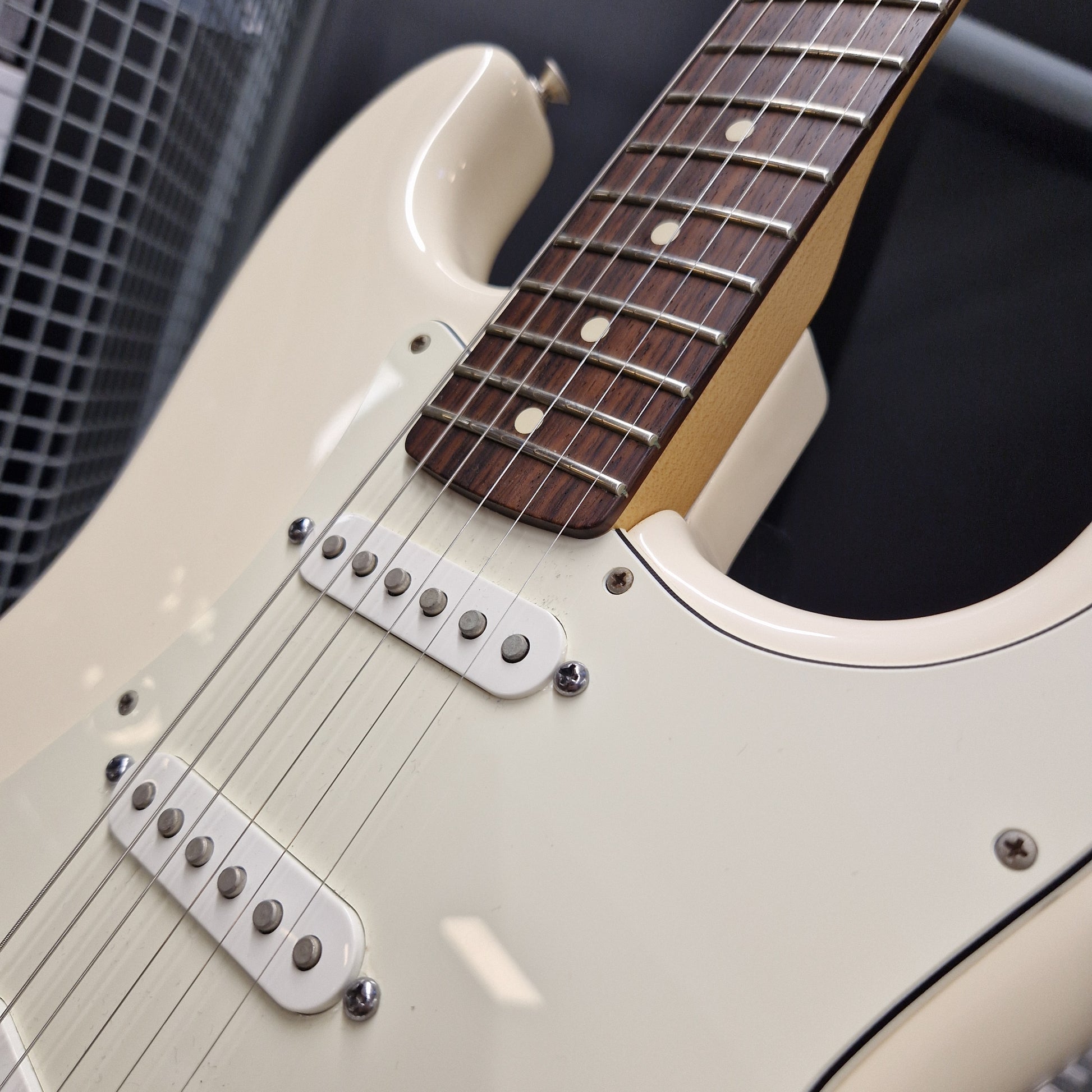 Pre-Owned Fender Standard Strocaster 2014 Electric - Arctic White Close-up of an electric guitar body in cream with a dark brown fretboard and silver hardware, photographed against a dark background.