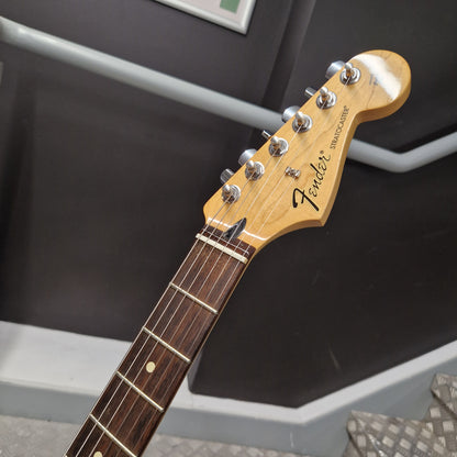 Pre-Owned Fender Standard Strocaster 2014 Electric - Arctic White Close-up of a Fender Stratocaster electric guitar headstock and upper neck, showing the natural wood finish, six silver tuning pegs, and dark fretboard against an indoor background.