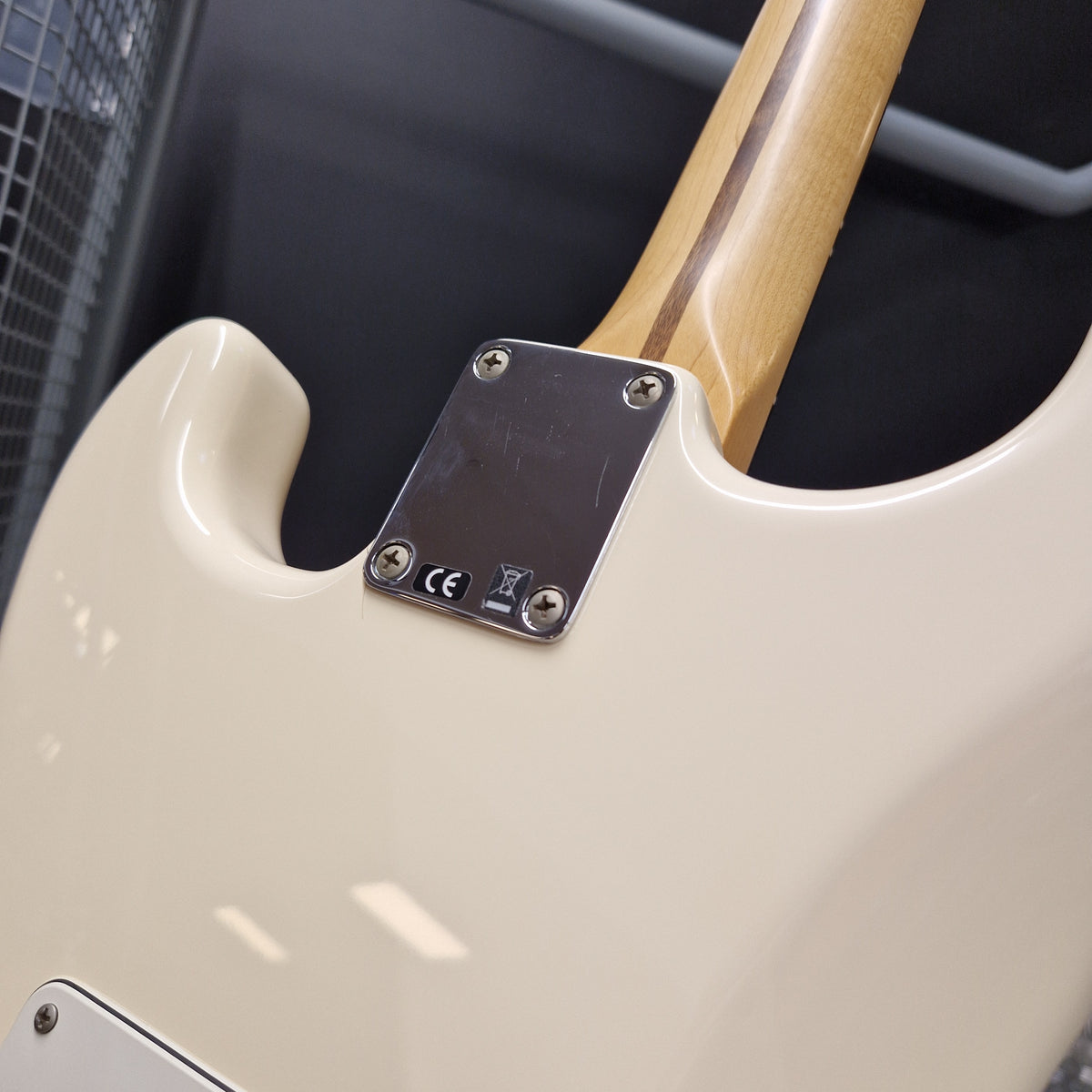 Pre-Owned Fender Standard Strocaster 2014 Electric - Arctic White Close-up of the rear body of an electric guitar with a cream-colored finish, a natural wood neck, and a silver metal plate secured with four screws.