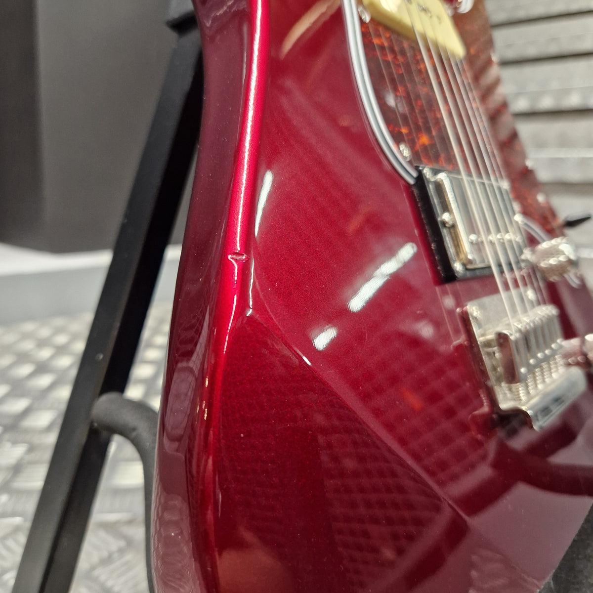 Pre-Owned Yamaha Pacifica 311H Electric - Red Metallic Close-up of a glossy red electric guitar body with chrome hardware and a black stand in the background.