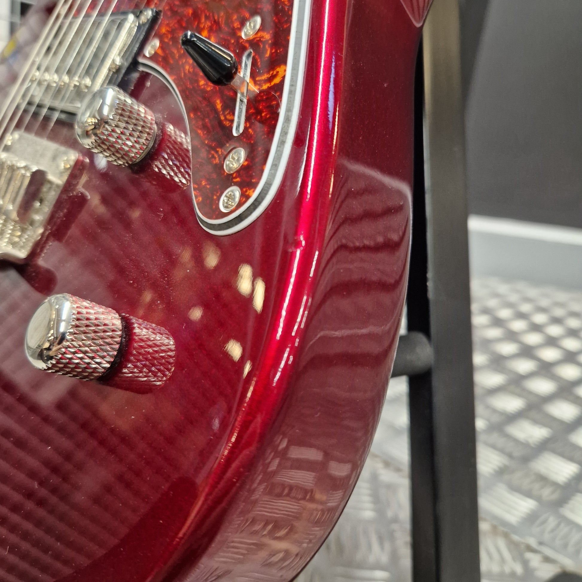 Pre-Owned Yamaha Pacifica 311H Electric - Red Metallic Close-up of a glossy red electric guitar body with chrome hardware, a black pickup, and a textured pickguard, photographed indoors against a dark and gray background.