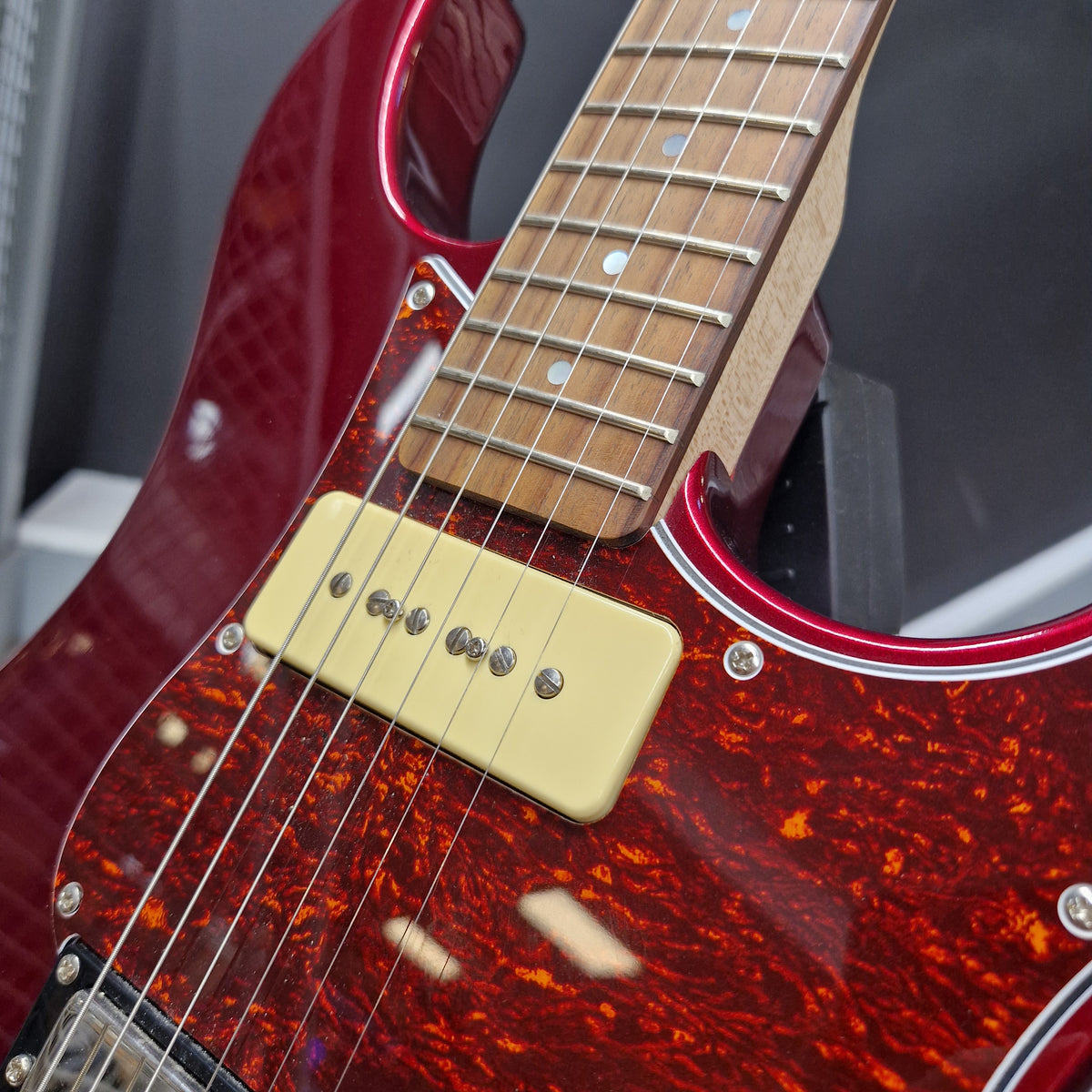 Pre-Owned Yamaha Pacifica 311H Electric - Red Metallic Close-up of an electric guitar body showing a glossy red maple finish with a dark tortoiseshell pattern, a cream single-coil pickup, and part of a light wood fretboard.