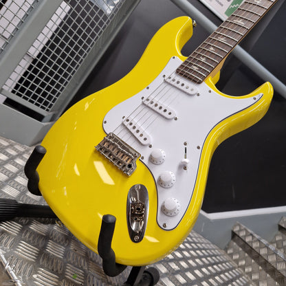 Pre-Owned PRS SE Silver Sky John Mayer Signature Electric - Dandy Lion A bright yellow electric guitar with a white pickguard and chrome hardware, resting on a black guitar stand on a metal diamond plate floor.