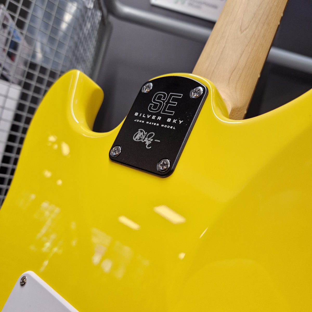Pre-Owned PRS SE Silver Sky John Mayer Signature Electric - Dandy Lion Close-up of a bright yellow electric guitar body with a black metal plate reading 'SE SILVER SKY' and 'Loud Waver Model,' plus a light wood neck visible at the top.