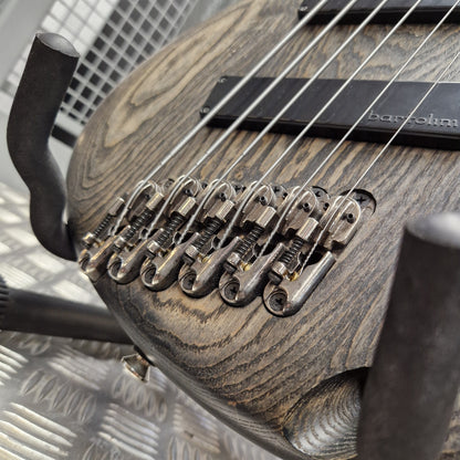 Pre-Owned Ibanez SRFF806 Multi-Scale 6-String Bass - Black Stained Close-up of a double-cutaway bass guitar with a dark, distressed wood finish and black hardware, including a visible Bartolomeo headstock.