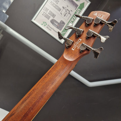 Pre-Owned Ibanez SRFF806 Multi-Scale 6-String Bass - Black Stained Close-up of the headstock of a wooden acoustic guitar, showing six silver tuning pegs and printed brand markings on a dark gray background.