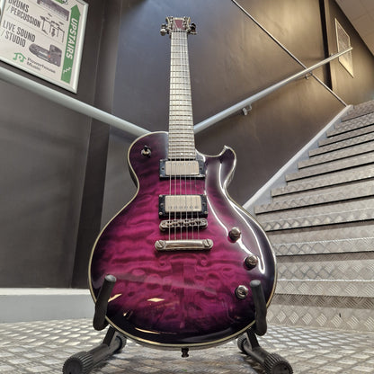 Pre-Owned Schecter Hellraiser Hybrid Solo-II Electric - Transparent Purple Burst A purple and magenta flame-tinted electric guitar on a stand, positioned in front of a staircase and dark wall.