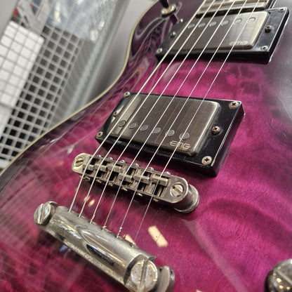 Pre-Owned Schecter Hellraiser Hybrid Solo-II Electric - Transparent Purple Burst Close-up of a purple electric guitar body with black humbucker pickups and chrome hardware, photographed indoors against a blurred metal grid background.