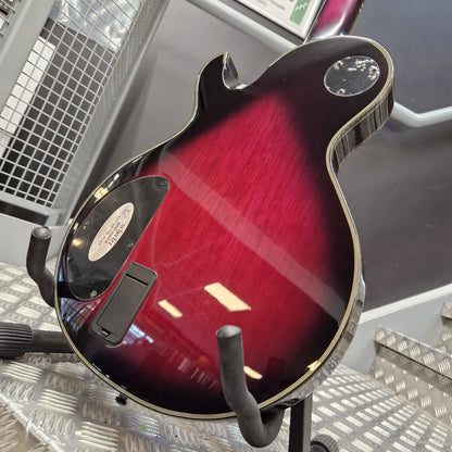 Pre-Owned Schecter Hellraiser Hybrid Solo-II Electric - Transparent Purple Burst Close-up of the back of an electric guitar body in a dark red to black sunburst finish, mounted on a stand in a shop setting.