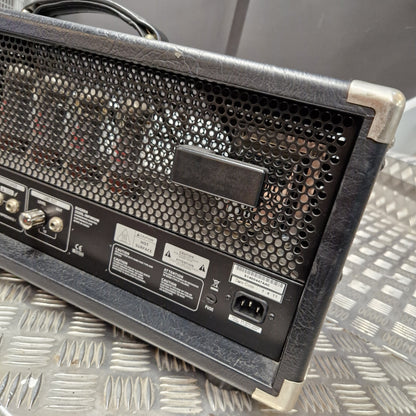 Pre-Owned Bugera 333XL Infinium 120w Electric Amplifer Head Close-up of the rear corner of a black guitar amplifier head with a perforated metal grille, control knobs, labels, and power input, resting on a diamond plate metal surface.